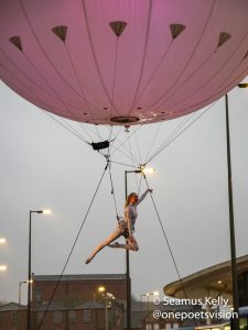 Performer suspended below a large balloon